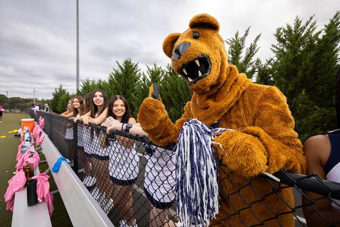 Nittany lion standing with cheerleaders