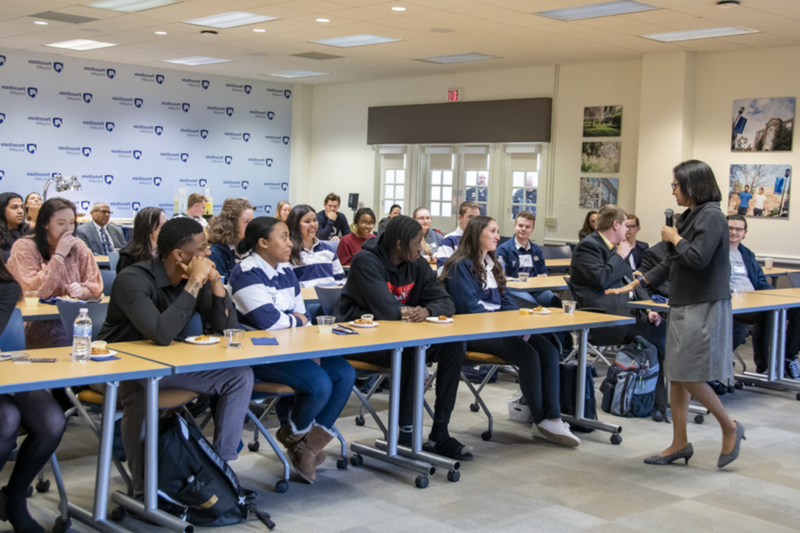 Woman with microphone speaks to classroom full of students