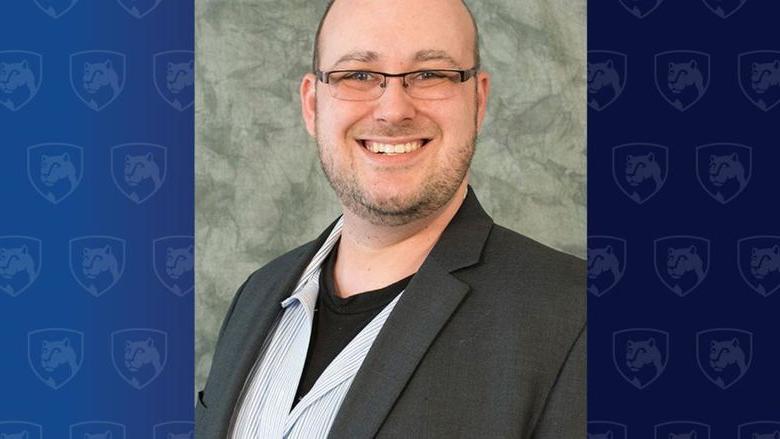 Head shot of a man with glasses in a dark jacket